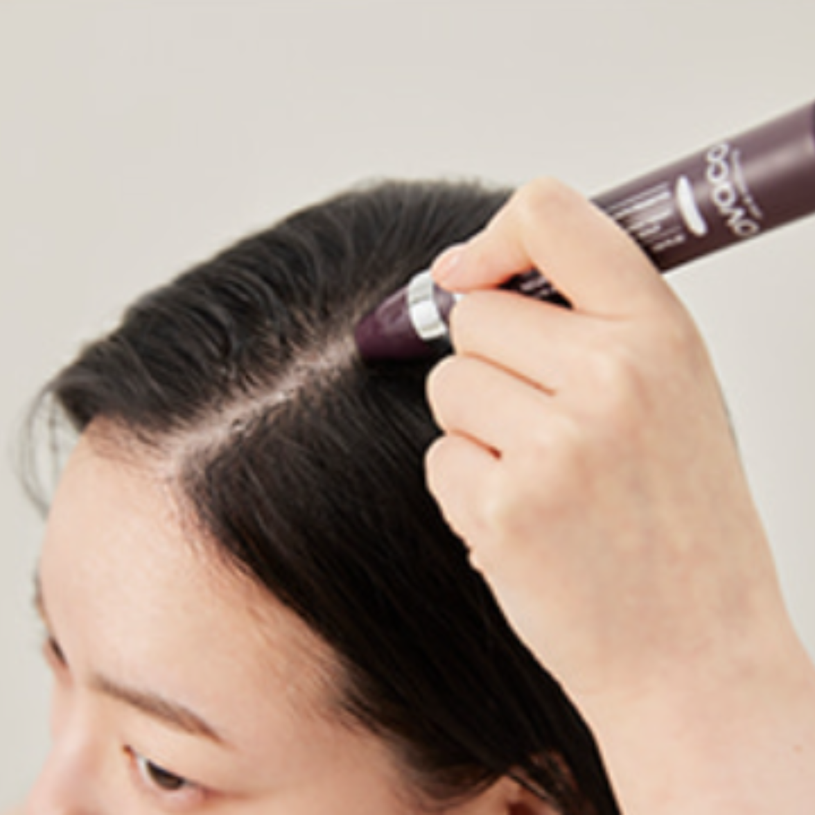 Woman using the Ovaco Biorepair Scalp Ampoule pen onto her hair part